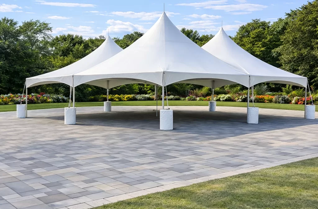 Large connected white high peak frame tent setup on a paver patio surrounded by green lawn in Erie County NY for an outdoor event