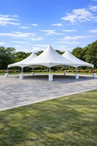 Large connected white high peak frame tent setup on a paver patio surrounded by green lawn in Erie County NY for an outdoor event