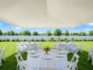 Interior view of a party tent rental in Erie County with formal table settings, white folding chairs, and sunflower arrangements under clear daylight